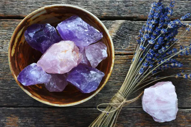 Bowl of raw Amethyst and Rose Quartz with dried lavender for jewelry saving lives.