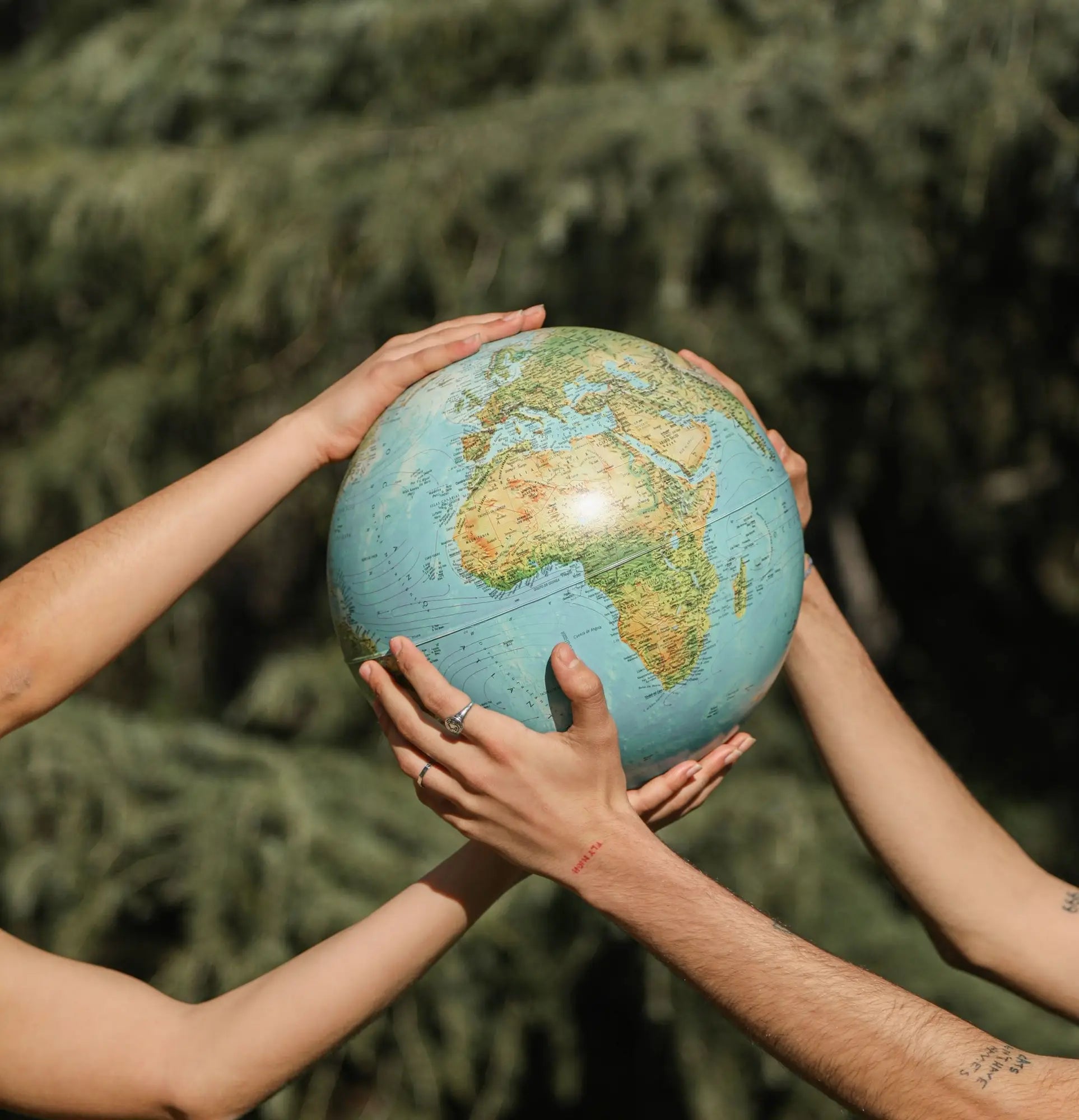 Hands lifting a globe highlighting Earth’s continents and oceans for Earth Day 2023.