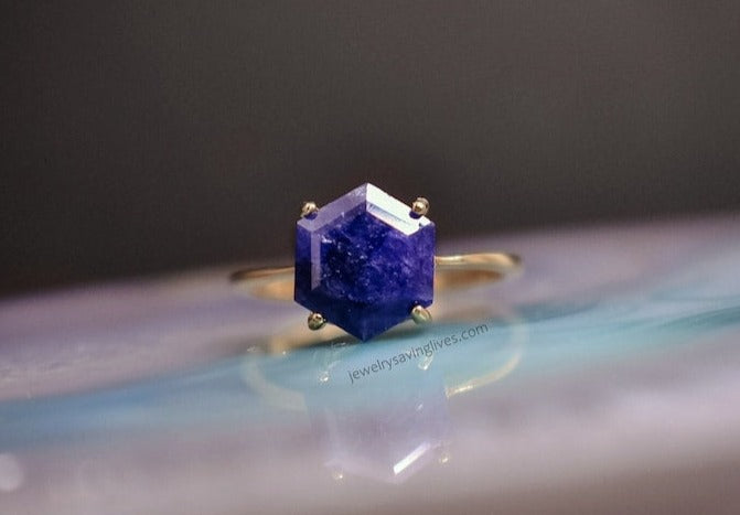 Hexagonal blue sapphire gemstone in gold ring, showcasing September birthstone beauty.