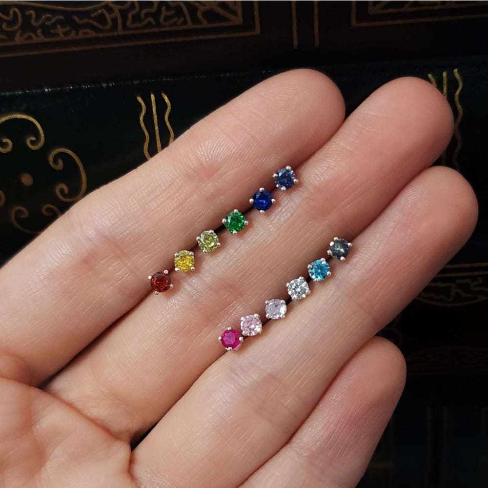 Colorful 3mm stud earrings displayed in two rows on a palm for stylish accessory selection