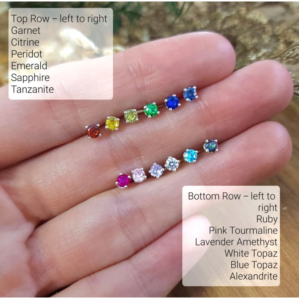 Colorful gemstones in rainbow pattern held in hand beside 3mm stud earrings