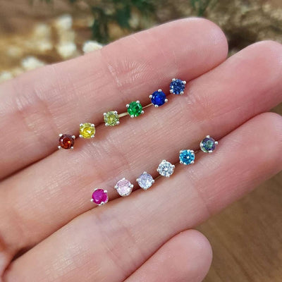 Colorful 3mm stud earrings arranged in a curve on a palm for vibrant accessory appeal