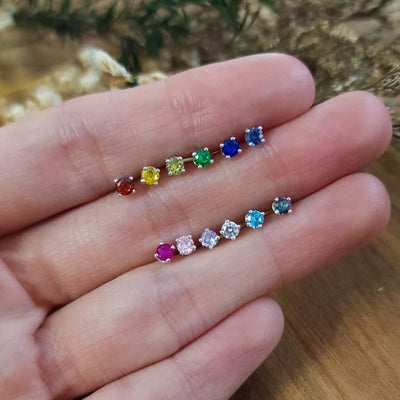 Colorful 3mm stud earrings displayed in two rows on an open palm