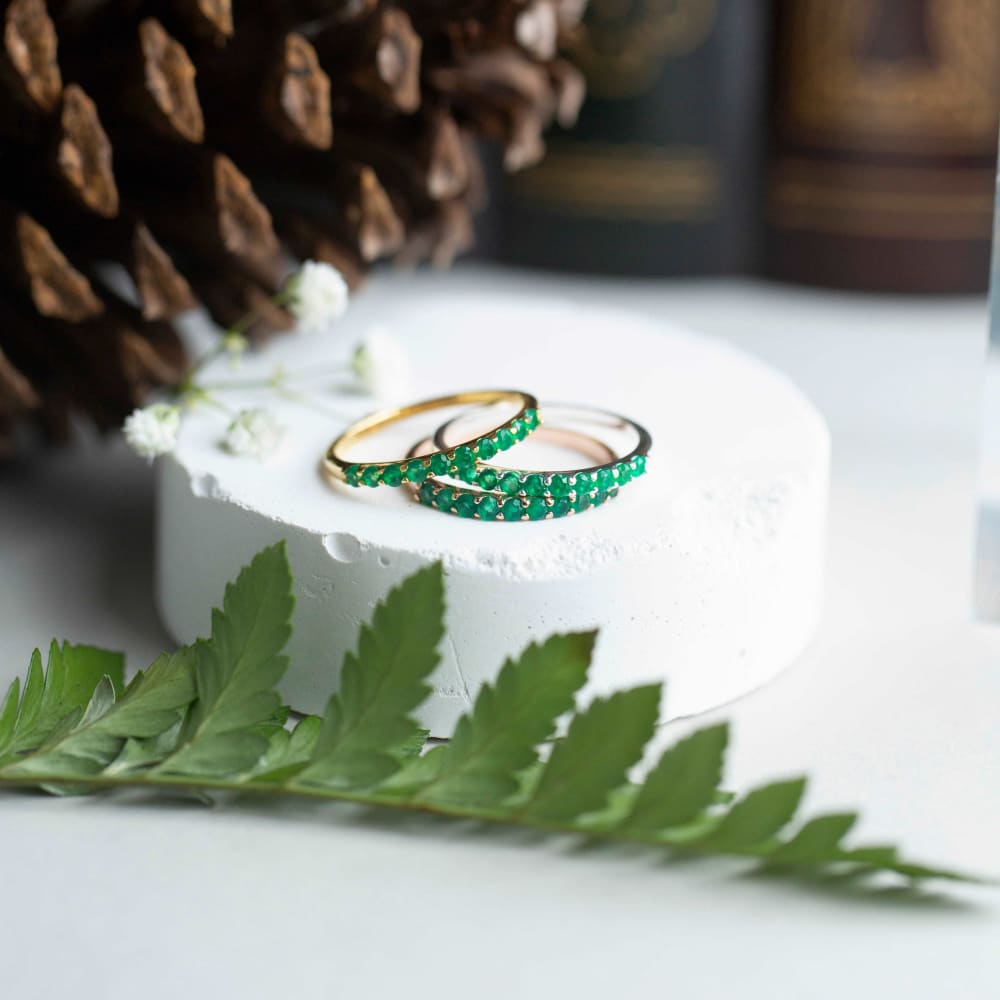 Two gold rings with emerald green stones from the Emerald Half Eternity Band collection