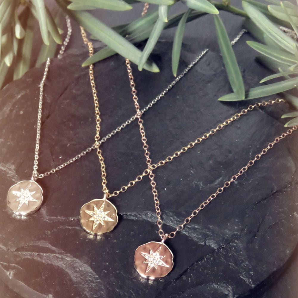 Three delicate celestial coin necklaces with star-shaped pendants in rose gold tones