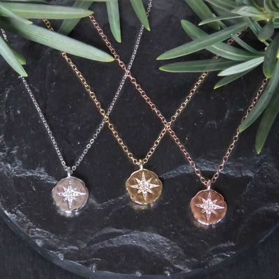 Three metallic compass pendant necklaces in silver, gold, and rose gold tones for Celestial Coin Necklace