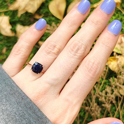 Square-cut sapphire ring on finger with lavender polish, showcasing the Blue Sandstone ring