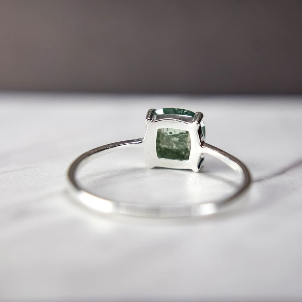 Silver ring featuring a glowing teal diamond in a square bezel setting