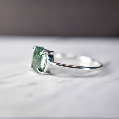 Silver ring featuring a glowing teal diamond gemstone in a square setting