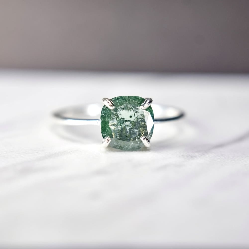 Silver ring with a cushion-cut glowing teal diamond in prong setting, The Asher