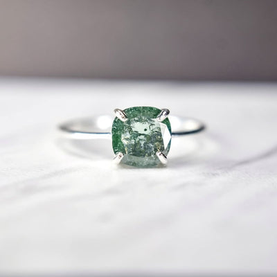 Silver ring with a cushion-cut glowing teal diamond in prong setting, The Asher