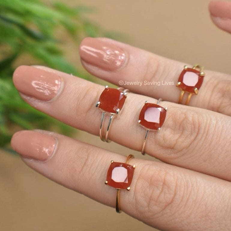 Four red natural carnelian rings in silver settings worn on nude nails, The Asher