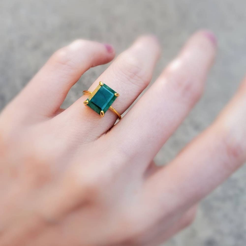 Gold ring with an emerald-cut green gemstone in The Audrey Natural Emerald design