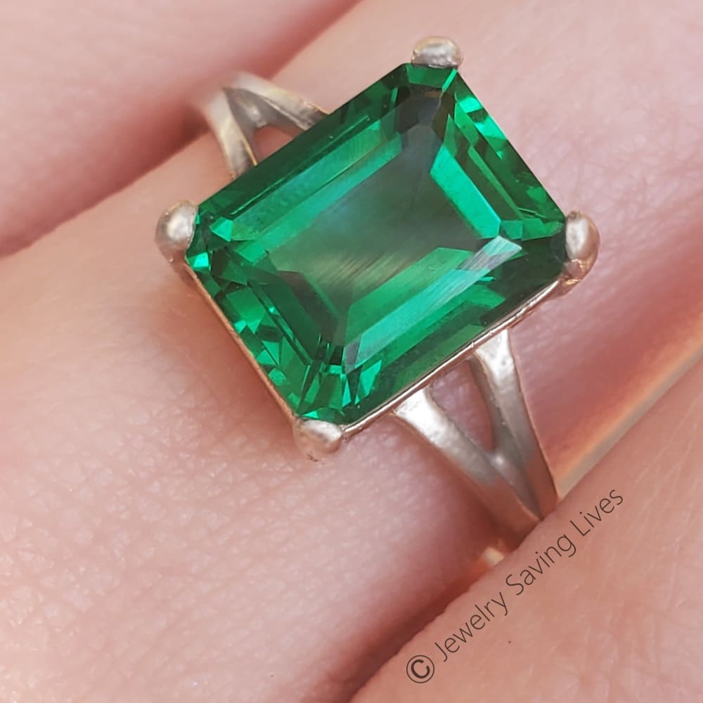 Emerald-cut green gemstone in The Audrina Emerald Ring, set in a sleek silver band